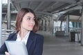 Front view of beautiful young Asian business woman holding ring binder and looking at far away at walkway outside office with copy Royalty Free Stock Photo