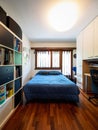 Front view bedroom with blue blankets, bookshelf and parquet