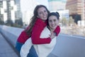 Front view of best smiling friends girls piggyback outdoors in the city Royalty Free Stock Photo
