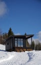 Front view of black modern wooden cabin on snowy mountains Royalty Free Stock Photo
