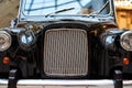 Front view of a black retro car. Part of black old car with headlamp and chrome radiator grill