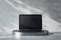 Front view on blank black modern laptop monitor with place for your logo or text on dark metallic round stand on abstract sunlit