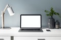 Front view on blank white laptop display on white table with stylish vase, lamp and smartphone. Mock up