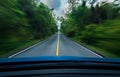 Front view of blue car driving with fast speed on the middle of asphalt road with white and yellow line of traffic symbol Royalty Free Stock Photo
