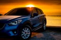 Front view blue compact SUV car with sport and modern design parked on concrete road by the sea at sunset. Electric car technology Royalty Free Stock Photo
