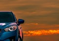 Front view of blue compact SUV car with sport and modern design parked on concrete road at sunset with beautiful orange sky. Royalty Free Stock Photo