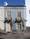 Front view of blue facade with white closed windows and door under clear blue sky. A blue house in a Tenerife town showing sash