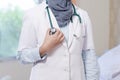 Front view body part of hijab female doctor hand holding stethoscope head inside a hospital room using white lab coat and grey sca Royalty Free Stock Photo