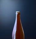 Front view of a bottle of cold beer with overflowing foam against blue grunge background. Organic photography. Royalty Free Stock Photo