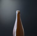 Front view of a bottle of cold beer with overflowing foam against dark blue grunge background. Royalty Free Stock Photo