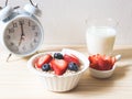 Breakfast set, oat or granola in white bowl, fresh blueberries and strawberries, a  glass of milk and white vintage alarm clock 7 Royalty Free Stock Photo