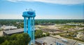 Front view of bright blue Auburn water tower with industrial view below structure aerial