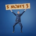 Front view of a businessman holding up the title `Money` with dollar signs on both sides.