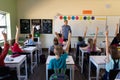 Male school teacher standing in an elementary school classroom with a group of school children Royalty Free Stock Photo