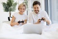 Front view of caucasian playing video games while lying under blanket at home. Royalty Free Stock Photo