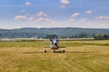 Front view of Cessna 172 airplane standing on grass field with blue cloudy sky on the background.