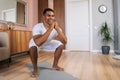 Front view of cheerful African-American man exercising and doing squats online in front of laptop. Royalty Free Stock Photo