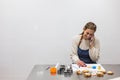 Pastry chef talking to her cell phone while making cookies with different shapes