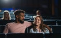 Front view of cheerful young couple in the cinema, watching film.