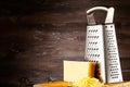 front view on cheese and grater lying on old burned cutting board. Royalty Free Stock Photo