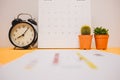 front view. clock, calendar and plant placed on yellow table background with copy space. image for