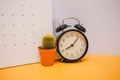 front view. clock, calendar and plant placed on yellow table background with copy space. image for