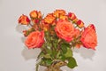 Ceramic vase, filled with four long stemmed, orange roses and a dozen baby, orange and red roses