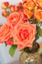 Ceramic vase, filled with four long stemmed, orange roses and a dozen baby, orange and red roses