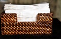 Weaved wood napkin holder, lacquered and filled with white napkins Royalty Free Stock Photo