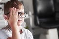 Front view. Close right eye with your hand. Little boy checking his vision with new black glasses