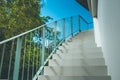 Front view close up of empty white concrete staircase and metal railing at outside buildings with blue sky background. Royalty Free Stock Photo