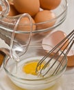 Mixing eggs and cream in clear dish with metal whisk, on a wood cutting board