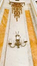 Front view close-up of a vintage wall lamp with candlesticks on the background of an elegant ornate wall.