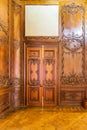 Closed elegant lumber door with engraved decorations, installed in wooden ornamental archway Royalty Free Stock Photo