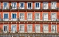 Front view of a colorful orange facade with white doors or jalousies. Balconies with white shutters or blinds