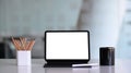 Computer tablet with empty screen, pencil holder and coffee cup on white office desk. Royalty Free Stock Photo