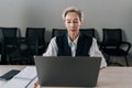 Front view of confident middle-aged business woman in suit sitting at desk working typing on laptop computer looking to Royalty Free Stock Photo