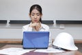 Front view of confident young Asian businesswoman working on the workplace in modern office. Thinking and thoughtful business conc Royalty Free Stock Photo