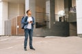 Front view of confused handsome male courier with thermo backpack using navigation app on phone standing in city street. Royalty Free Stock Photo