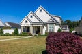 The front view of a cottage craftsman style white house with a triple pitched roof with a sidewalk, landscaping and curb Royalty Free Stock Photo