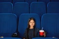Little smiling girl sitting in empty cinema.