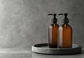 A front view 3D rendering of two brown plastic cosmetic containers with labels, shampoo bottles laying on gray background Royalty Free Stock Photo