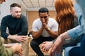 Front view of depressed African American young man sharing problem sitting in circle on group therapy session. Royalty Free Stock Photo