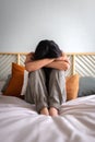 Front view of depressed and sad young woman sitting on the bed crying. Vertical image. Sadness and mental health Royalty Free Stock Photo