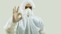 Doctor with mask and bioprotective suit with arm extended forward and his right hand making an OK sign on white background Royalty Free Stock Photo