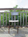 Front view of empty rusty outdoor chair leaning on wooden fence and greenery background. Tropical and Caribbean culture. French