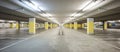 Front view empty underground supermarket parking with yellow concrete columns and white arrow on the ground Royalty Free Stock Photo