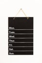 Front view of empty weekly to do list white grid timetable schedule on black chalkboard hanging on wall Royalty Free Stock Photo