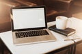 Front view. Empty workplace. On white coffee table is laptop with blank screen, cup of coffee, notebook, pen, newspaper. Royalty Free Stock Photo