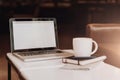 Front view. Empty workplace. On white coffee table is laptop with blank screen, cup of coffee, notebook, pen, newspaper. Royalty Free Stock Photo